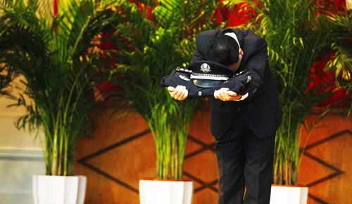 原市局刑警總隊(duì)二支隊(duì)副支隊(duì)長(zhǎng)鄭某手托警服警帽向全場(chǎng)鞠躬。圖片來(lái)源：重慶晚報(bào)