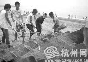 大連市金石灘國賓浴場(chǎng)，工作人員將帶有油污的沙子清理掉。