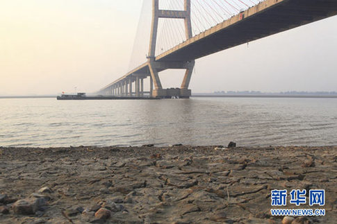 這是12月10日在江西省湖口縣境內(nèi)的鄱陽(yáng)湖大橋附近拍攝的已經(jīng)干涸開裂的湖灘。