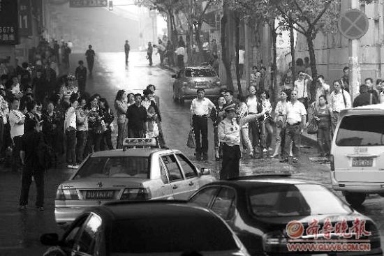  8日，在青島15中考點(diǎn)外，家長(zhǎng)排起人墻堵路，交警只能指揮途經(jīng)車(chē)輛繞行。 本報(bào)記者 楊寧 張曉鵬 攝