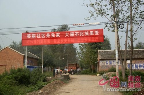 死者的家屬在村口迎接前來吊唁的親友，紅色的橫幅看上去更具諷刺意味。