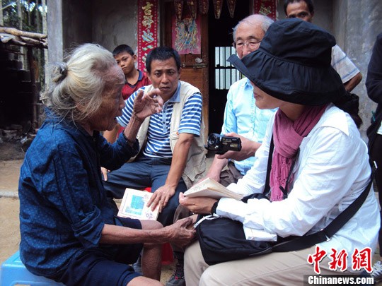 日本“海南島近代史研究會”創(chuàng)始人佐藤正人第22次到海南島調(diào)查日本侵瓊史。圖為在保亭黎族苗族自治縣南林鄉(xiāng)羅葵村，金靜美握著86歲老人林亞金的手。中新社發(fā) 張茜翼 攝