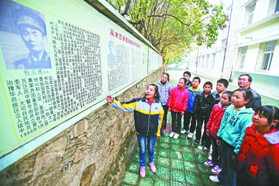 上圖：學校文化墻前，小講解員講述開國將軍杜義德的故事。記者何曉剛 攝